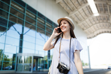 Young traveler tourist woman with retro vintage photo camera talking on mobile phone calling friend, booking taxi, hotel at airport. Passenger traveling abroad on weekends getaway. Air flight concept.
