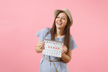 Portrait of happy woman in blue dress, hat holding periods calendar for checking menstruation days isolated on bright trending pink background. Medical, healthcare, gynecological concept. Copy space.