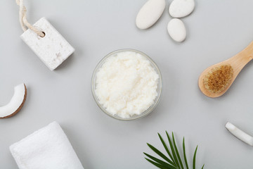 Body scrub of coconut oil, sugar and shavings in glass jar from above. Homemade cosmetic for peeling and spa care. Flat lay.