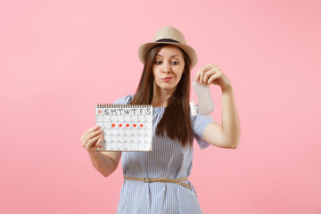 Woman in blue dress, hat holding sanitary napkin, tampon female periods calendar, checking menstruation days isolated on pink background. Medical, healthcare, gynecological choice concept. Copy space.