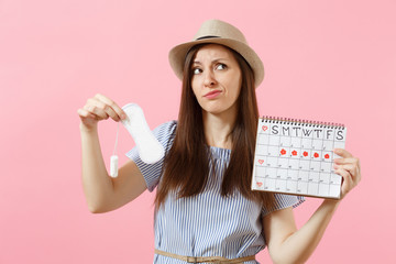 Woman in blue dress, hat holding sanitary napkin, tampon female periods calendar, checking menstruation days isolated on pink background. Medical, healthcare, gynecological choice concept. Copy space.