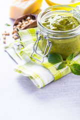 Pesto sauce in glass jar and ingredients. 