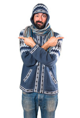 Man with winter clothes pointing to the laterals having doubts