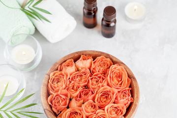 Obraz na płótnie Canvas Bowl with fresh wet rose and essential oil bottle for spa, wellness and aromatherapy.