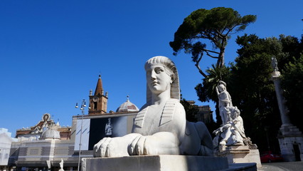 Obraz premium biały sfinks leży na balustradzie na Piazza del Popolo w Rzymie na tle stalowego błękitnego nieba