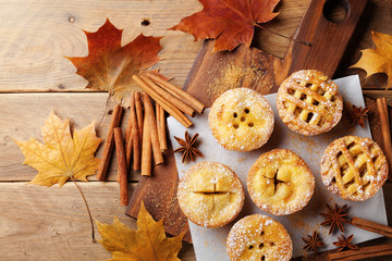 Delicious mini apple pies on rustic wooden table. Autumn pastry desserts. © juliasudnitskaya