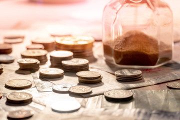 Sand running through the shape of hourglass on table with banknotes and coins of international currency. Time investment and retirement saving. Urgency countdown timer for business deadline concept