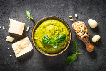 Pesto sauce with ingredients on dark stone table. 