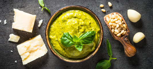Pesto sauce with ingredients on dark stone table. 