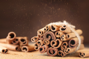 Obraz na płótnie Canvas Heap of cinnamon sticks and cinnamon powder dust effect. Aromatic spice.