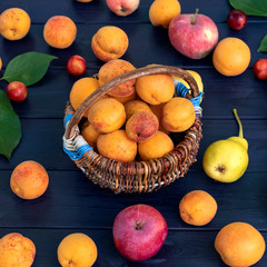 Still life of various fruits and berries on blue wooden background. Square photo.