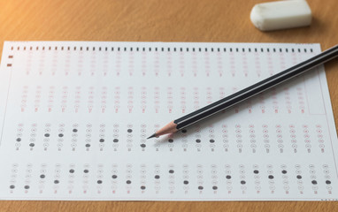 Black pencil on paper computer sheet and eraser on table.  Standardized test form with answers bubble. Multiple choice answer sheets. Ideas about education.