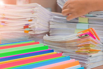 Businessman hands working in pile of unfinished paperwork for searching information on work desk office. Stack of business paper. Report papers stacks. Business and finance concept.