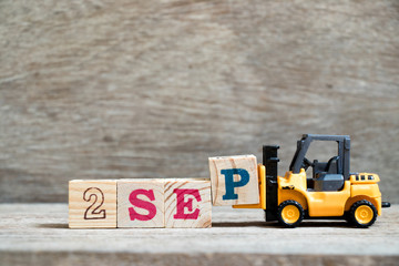 Toy forklift hold block P to complete word 2 sep on wood background (Concept for calendar date in month September)