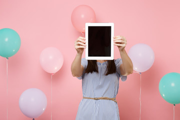 Portrait of young brunette woman wearing blue dress holding covering face with tablet pc computer...