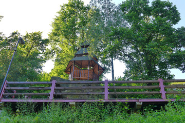 A small gazebo on the stone is surrounded by tall trees