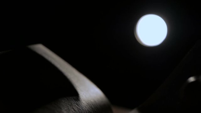 Close-up of an open book at night in a ray of light. Pages are heard from the wind