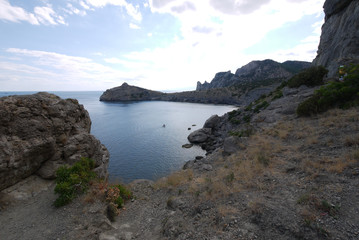The wide bay is surrounded by high Crimean rocks covered with grass