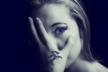 Obraz premium Portrait of a scared woman with a tattoo hand on her face artistic conversion