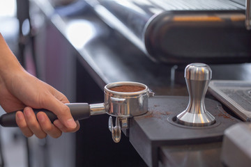 Pressing coffee with tamper before brew. Selective focus