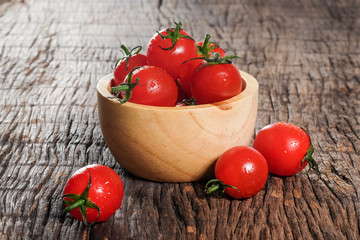 Ripe cherries tomatoes or mini tomatoes in a wooden bowl.