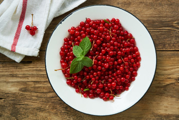 Ripe red currant in a bowl on a wooden background    