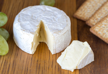 Camembert cheese and crackers close up on wooden board