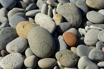 Natural close up image of multi- coloured, sea washed pebbles on a shingle beach. Sun kissed with shadowing. Kolymvari, Crete