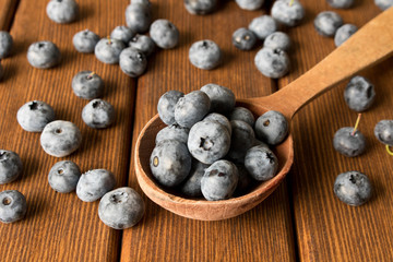 Fresh blueberries on an old wooden table in a wooden spoon. Close up. The concept of natural food