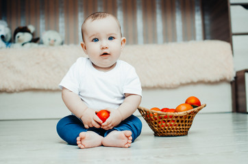 little baby girl sitting on the floor and playing with tomatoes