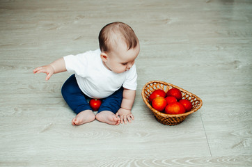 little baby girl sitting on the floor and playing with tomatoes