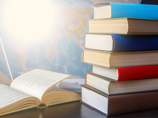 Composition of books and studies on table with world map hanging on wall