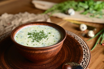 Summer yoghurt cold soup with radish, cucumber, and dill on wooden table. Okroshka.