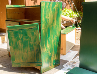 Old broken cabinet, which is prepared with a first coat of green paint for further repair and...