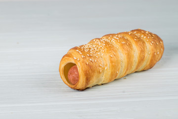 Sausages wrapped in puff pastry. Sausages in a dough on a wooden background