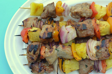 Grilled Pork with Pineapple and Vegetables; close-up of skewered kebabs piled on a platter.