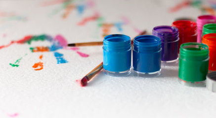 Opened bottles of poster color and brush on white background with copy space. Select focus shallow...