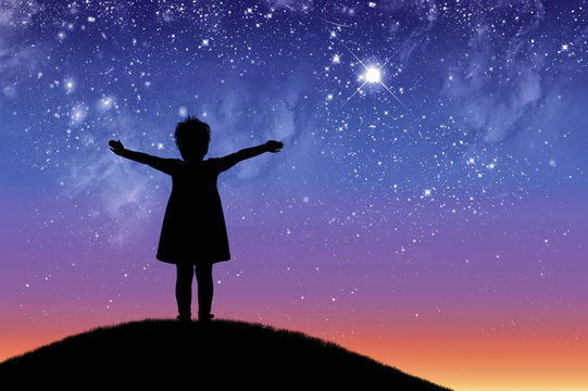 Silhouette, little happy girl child standing on a hill looking not starry beautiful sky.