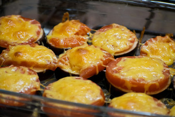 Summer food: hot eggplant with cheese and tomatoes close up. Baked eggplant with tomatoes and cheese.