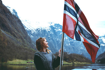Panorama of fjord. Tourist girl with the flag of Norway enjoys a beautiful view of the fjord and...