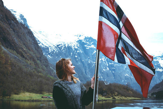Panorama of fjord. Tourist girl with the flag of Norway enjoys a beautiful view of the fjord and mountains