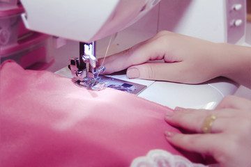 The hand of the seamstress on the sewing machine make the dress