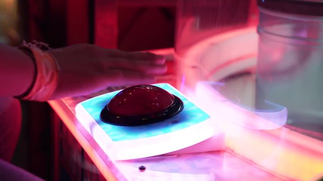 Person Rapidly smashing a big red button at an arcade game