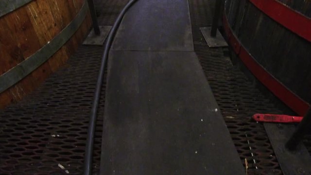 Panning up wooden cat-walk on iron grating floor between wooden tubs