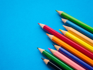 Closeup color pencils isolated on blue paper background. Education, Back to school Concept.
