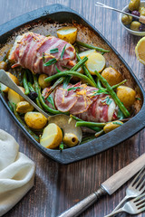 Bacon-wrapped haddock stuffed with crayfish tails, with lemony new potatoes, green beans and olives - high angle view