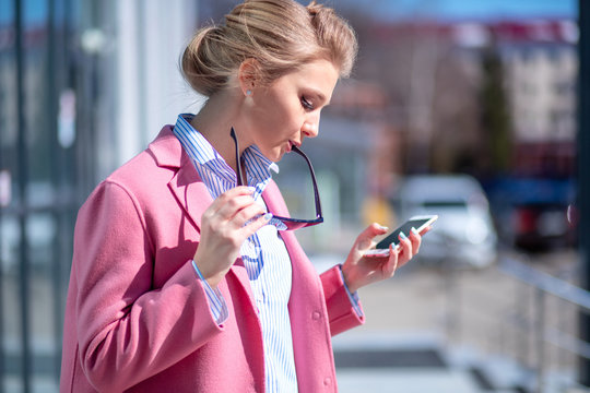 young awesome woman dialing the number. order sushy by phone. girl with glasses on her lips looking at the screen of the cell phone