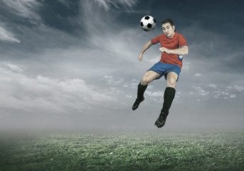 Football player with ball in action under sky with clouds