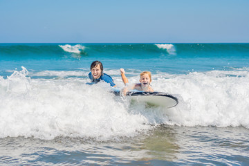 Father teaching his young son how to surf in the sea on vacation or holiday. Travel and sports with children concept