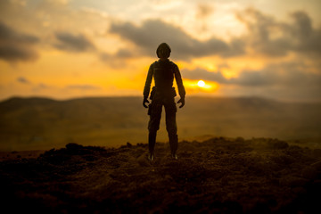 Silhouette of military soldier or officer with weapons at sunset. shot, holding gun, colorful sky, mountain, background. Decoration with toy soldier